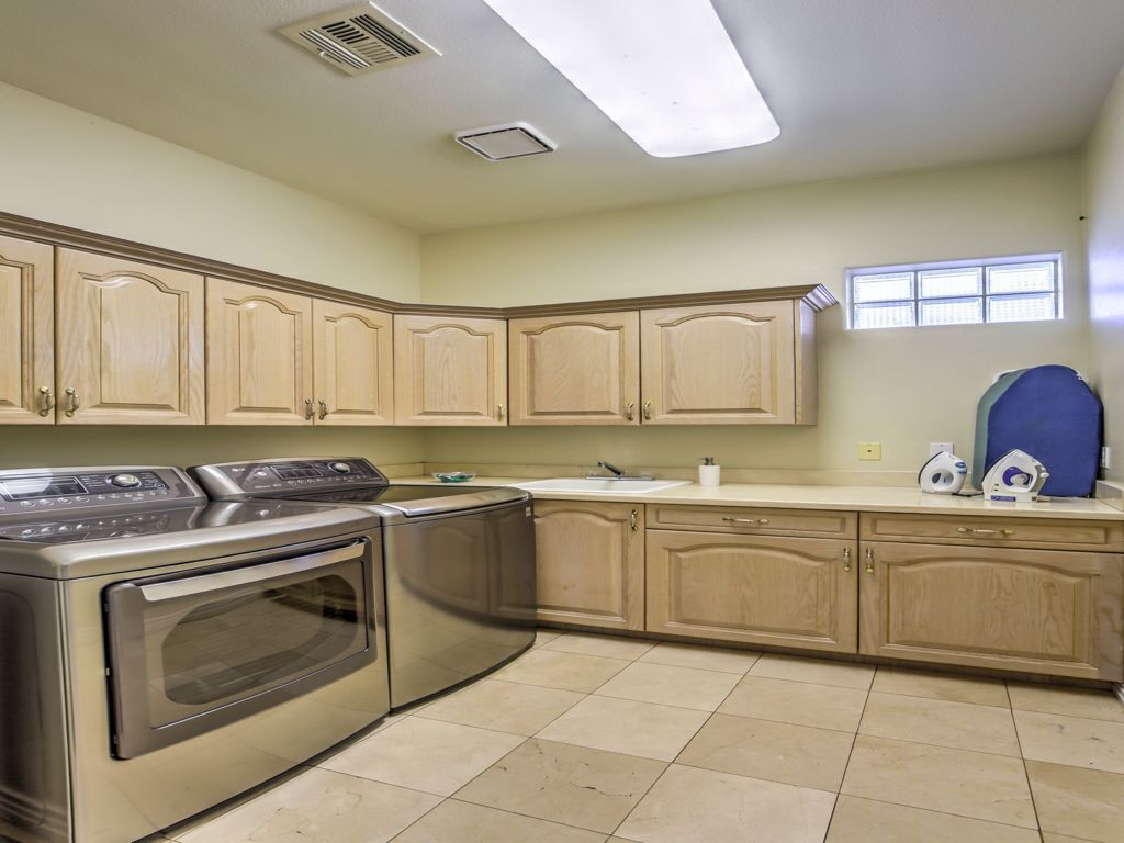 A kitchen with stainless steel appliances, beige cabinetry, and a window.