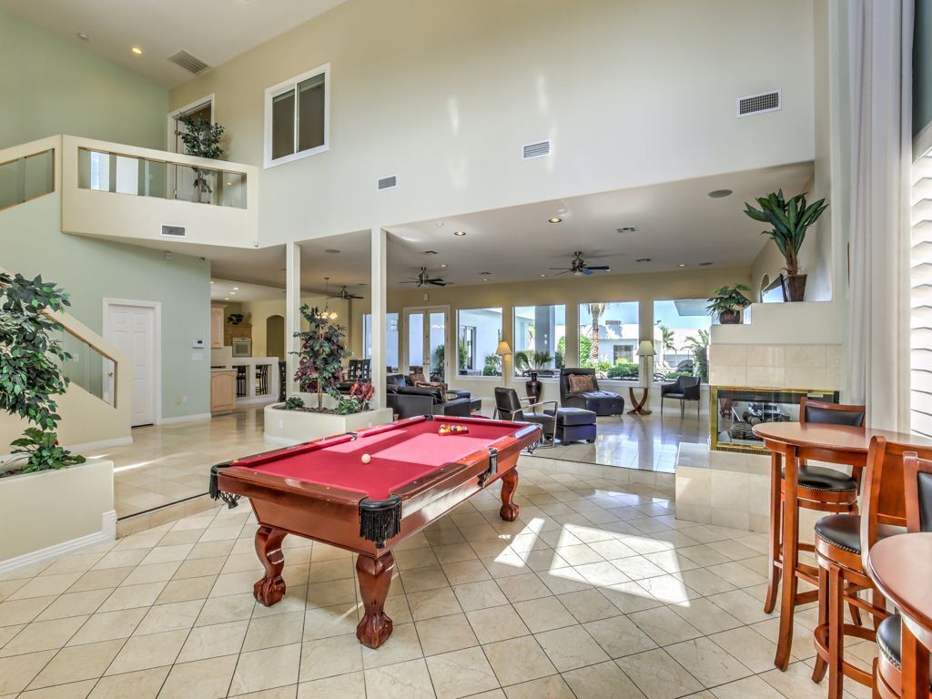 A spacious indoor area with a pool table, seating, and a staircase leading to an upper level.