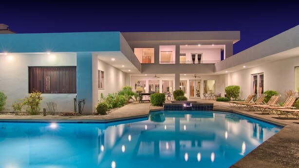 A modern house with a swimming pool, a covered patio, and a two-story structure.