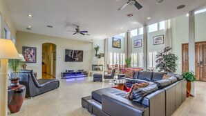 A spacious living area with a large sectional sofa, a dining table, and a ceiling fan.