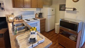 A compact kitchen with wooden cabinets, a white refrigerator, a stove, and a microwave. - Great Hunting, Fishing  and Family Vacation Getaway (Linden)