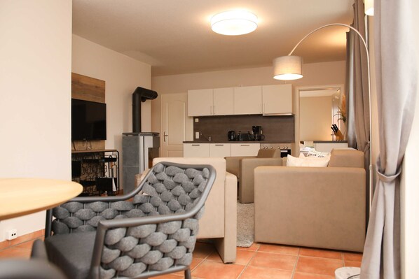 A compact living space with a kitchenette, a sofa, a dining table, and a chair.