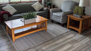 Een woonkamer met een bank, fauteuil, salontafel en vloerkleed.