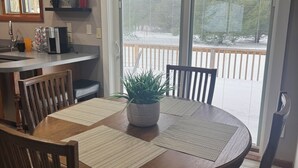 Een eetruimte met een ronde tafel, stoelen, een koffiebar en uitzicht op een balkon.