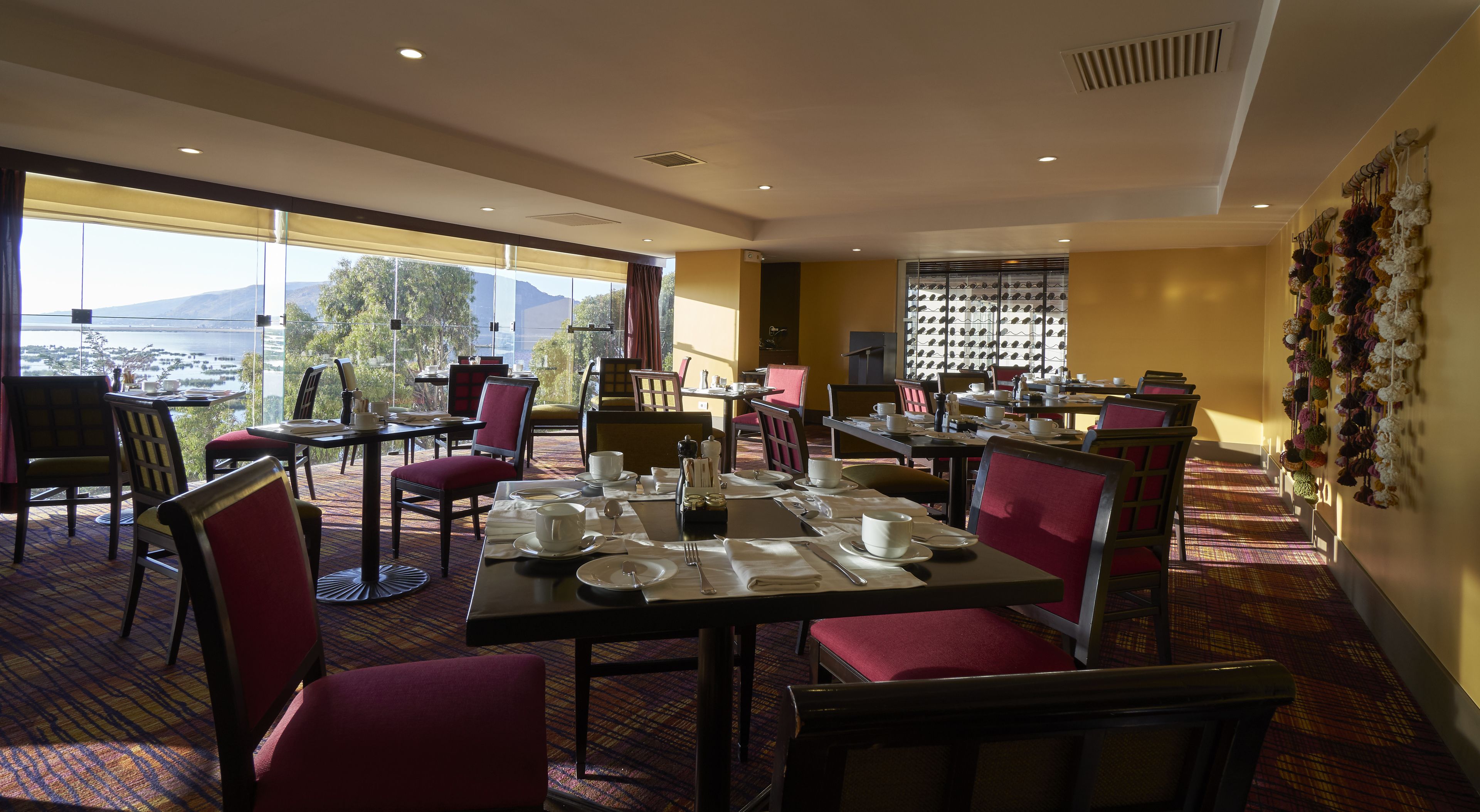 A dining area with tables set for service, chairs, and a view of a lake and mountains.