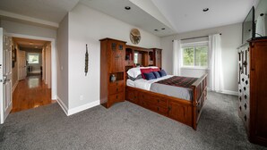 A bedroom with a large bed, wooden dresser, and a window with curtains. - Spacious Suite on Oregon Equestrian Estate (Tualatin)
