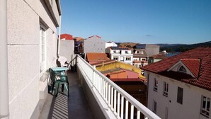 Un balcone con vista su edifici, un tavolo e delle sedie.