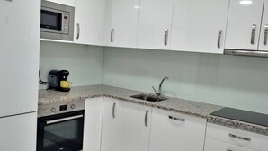 Cucina con mobili bianchi, un forno a microonde, una macchina da caffè e un lavello.