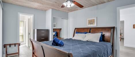 A bedroom with a wooden bed, a ceiling fan, and a view of the outside.