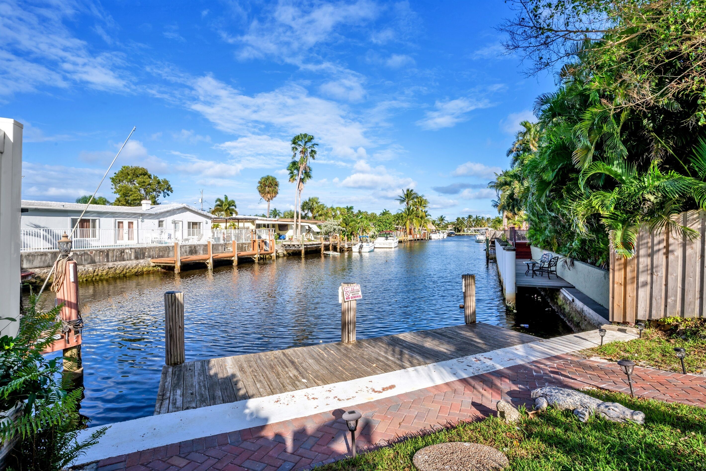A waterfront property with a dock, a small boat, and a paved walkway.
