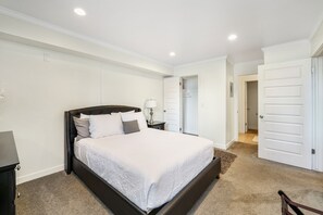 Ein Schlafzimmer mit einem großen Bett, einem Nachttisch, einer Lampe und einem Kleiderschrank.
