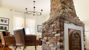 A living room with a brick fireplace, wooden furniture, and a chandelier. - The RED DOOR: Explore Pensacola's Downtown Entertainment next to Wedding Venues! (Pensacola)
