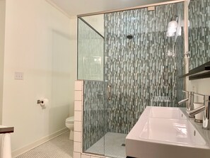 Une salle de bain avec une douche à parois de verre, un lavabo blanc et des toilettes.