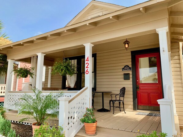 Une maison en bois avec un porche, une porte rouge et une plaque portant le numéro 426.