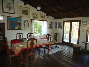 Enjoy meals in this cozy dining area with a wooden table and chairs, surrounded by framed artworks and natural light.