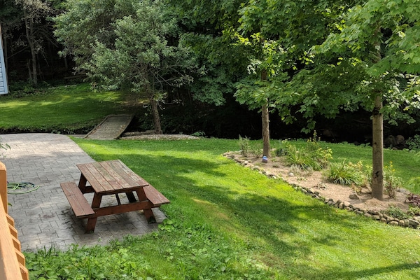 Very large yard for your use with picnic table + bridge over creek to fire pit.