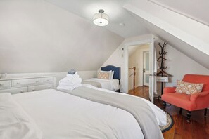 Une chambre à coucher avec un grand lit, une chaise, une table de chevet et une armoire.