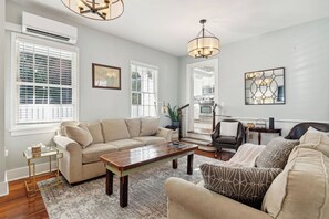 A living room with a sofa, coffee table, and a chair. There is a staircase leading to an upper level. - Downtown home 5BR & 7 Beds w/ Free Private Parking (Charleston)