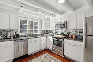 A modern kitchen with white cabinetry, stainless steel appliances, and a window with blinds. - Downtown home 5BR & 7 Beds w/ Free Private Parking (Charleston)