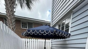 A patio with a table and chairs, a white picket fence, and a house in the background. - Downtown home 5BR & 7 Beds w/ Free Private Parking (Charleston)
