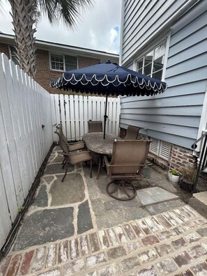 A patio with a table and chairs, a white picket fence, and a house in the background. - Downtown home 5BR & 7 Beds w/ Free Private Parking (Charleston)