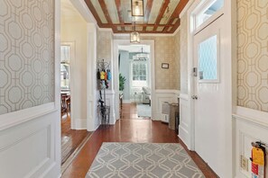 A hallway with patterned wallpaper, a wooden floor, a patterned rug, and a ceiling with exposed beams. - Downtown home 5BR & 7 Beds w/ Free Private Parking (Charleston)