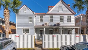 A two-story house with a white picket fence, a balcony on the upper floor, and a garage in the front. - Downtown home 5BR & 7 Beds w/ Free Private Parking (Charleston)