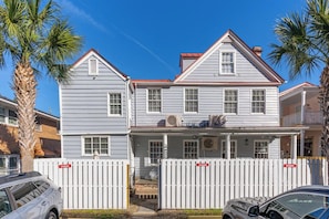A two-story house with a white picket fence, a balcony on the upper floor, and a garage in the front. - Downtown home 5BR & 7 Beds w/ Free Private Parking (Charleston)