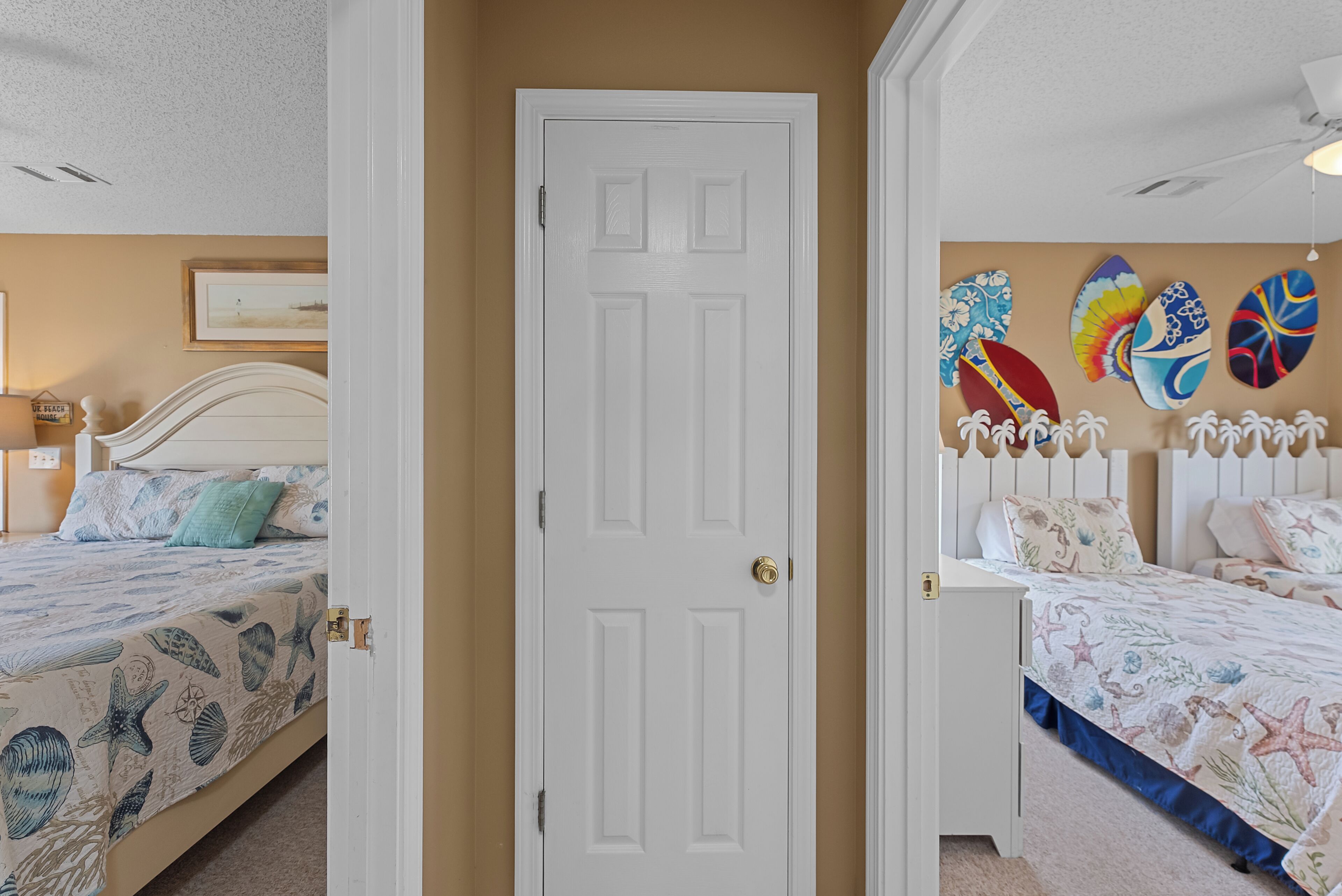 Une chambre avec deux lits, une porte blanche et un mur décoré de motifs de planches de surf.