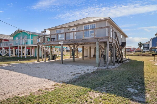 Une maison située en bord de mer, dotée d’une terrasse en bois et d’un escalier menant à l’entrée principale.
