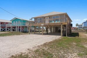 A beachfront hotel with a wooden deck, a covered area, and a clear sky.