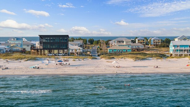 A beachfront property with a sandy beach, ocean view, and several buildings with large windows and balconies. - Spacious house within walking distance from beach- less then 100 yards (Gulf Shores)