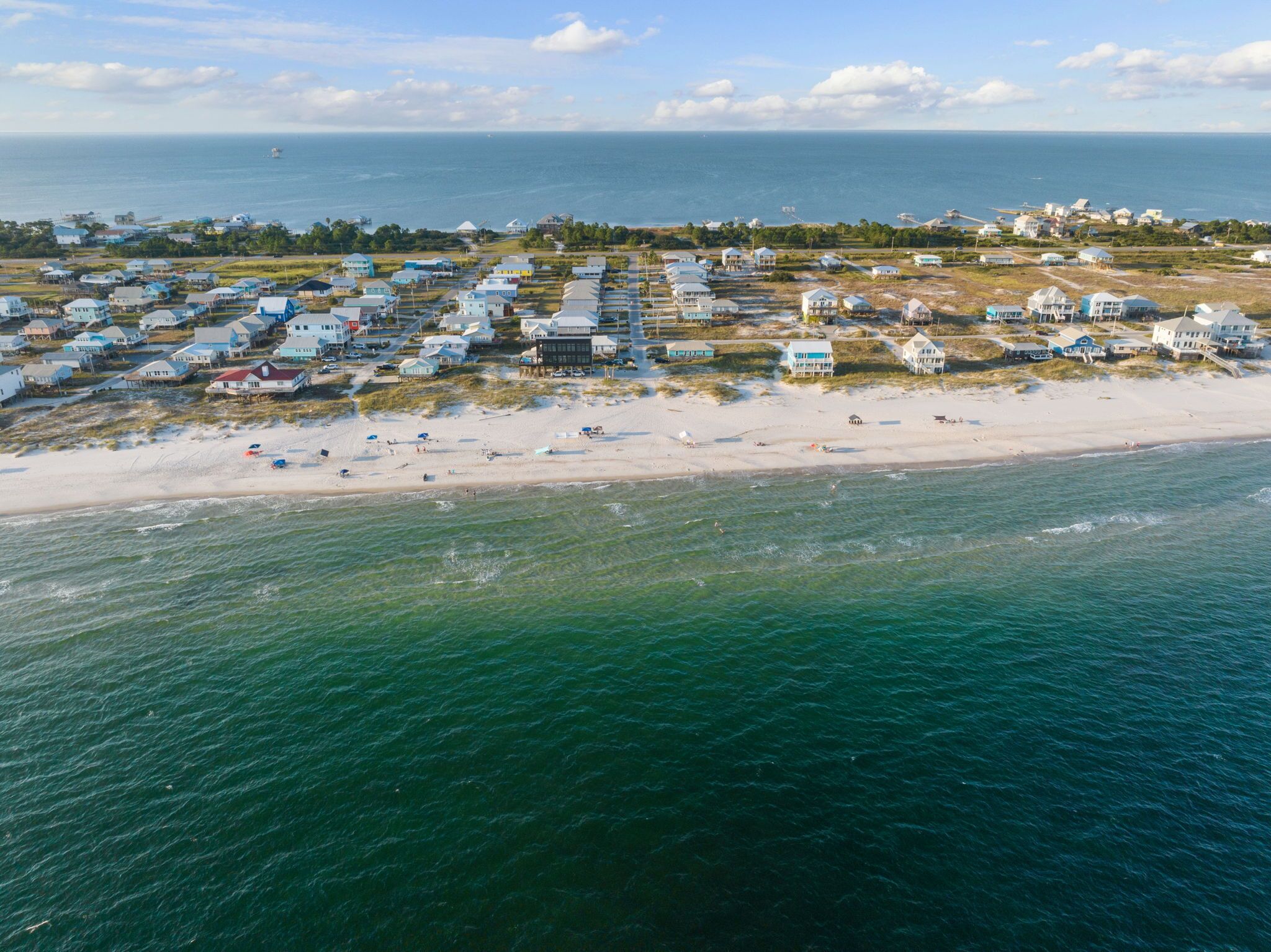 An aerial view of a coastal resort with beachfront villas and a sandy beach.