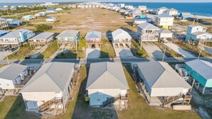A coastal residential area with multiple houses featuring gabled roofs and wooden decks, some with attached porches. - Spacious house within walking distance from beach- less then 100 yards (Gulf Shores)