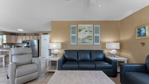 A living room with a recliner, sofa, coffee table, and a kitchen in the background. - Spacious house within walking distance from beach- less then 100 yards (Gulf Shores)