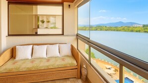 Una stanza con un'ampia finestra vista su un corpo d'acqua, soffitto in legno e un divano con cuscini.