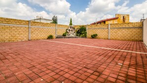 A courtyard with a brick floor, a stone fountain, and a yellow brick wall. - OYO Hotel Familiar Tollan Cholula (San Pedro Cholula)
