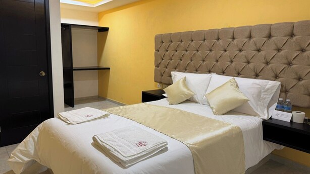 A hotel room with a large bed, a headboard, a nightstand, and a door. - OYO Hotel Familiar Tollan Cholula (San Pedro Cholula)