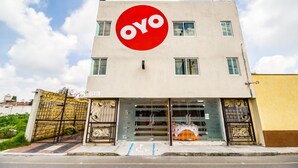 A building with a large red OYO logo, a gated entrance, and a clear sky. - OYO Hotel Familiar Tollan Cholula (San Pedro Cholula)