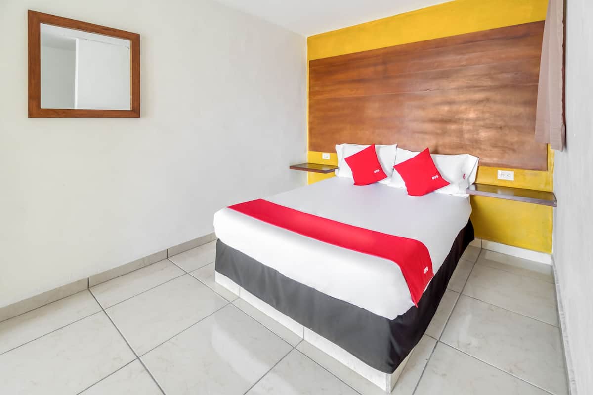Una habitación de hotel con una cama grande, un cabecero de madera y un espejo en la pared.