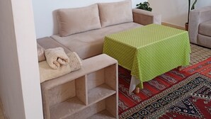 Una sala acogedora con un sofá, una mesa verde y una alfombra estampada.