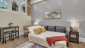 A bedroom with a bed, two bedside tables, a desk, and a chair.