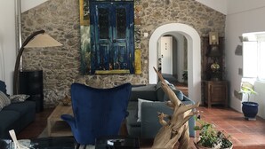 Un salon chaleureux avec un mur en pierre, un fauteuil bleu, une table basse en bois et une plante décorative.