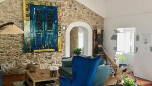 Un salon chaleureux avec un mur en pierre, une porte bleue et une table en bois agrémentée de plantes.