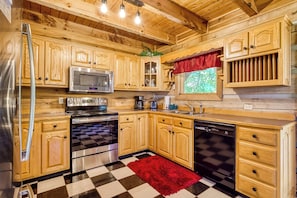 A kitchen with wooden cabinets, a stainless steel refrigerator, a microwave, an oven, a dishwasher, and a checkered floor. - Halfway to Heaven is perfect for a couples retreat or family getaway (Sevierville)