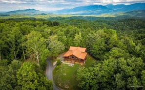A cabin surrounded by dense forest with a clear view of the surrounding mountains.