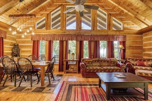 A log cabin interior with a dining area, sofa, and a ceiling fan. - Halfway to Heaven is perfect for a couples retreat or family getaway (Sevierville)