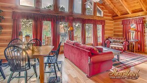 A cabin with a dining area, a red sofa, and a ceiling fan. - Halfway to Heaven is perfect for a couples retreat or family getaway (Sevierville)