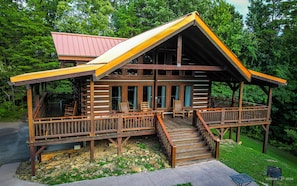 A log cabin with a porch, outdoor seating, and a staircase leading to the main entrance. - Halfway to Heaven is perfect for a couples retreat or family getaway (Sevierville)