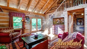 A cabin interior with a wooden ceiling, a staircase, a sofa, a coffee table, and a television. - Halfway to Heaven is perfect for a couples retreat or family getaway (Sevierville)